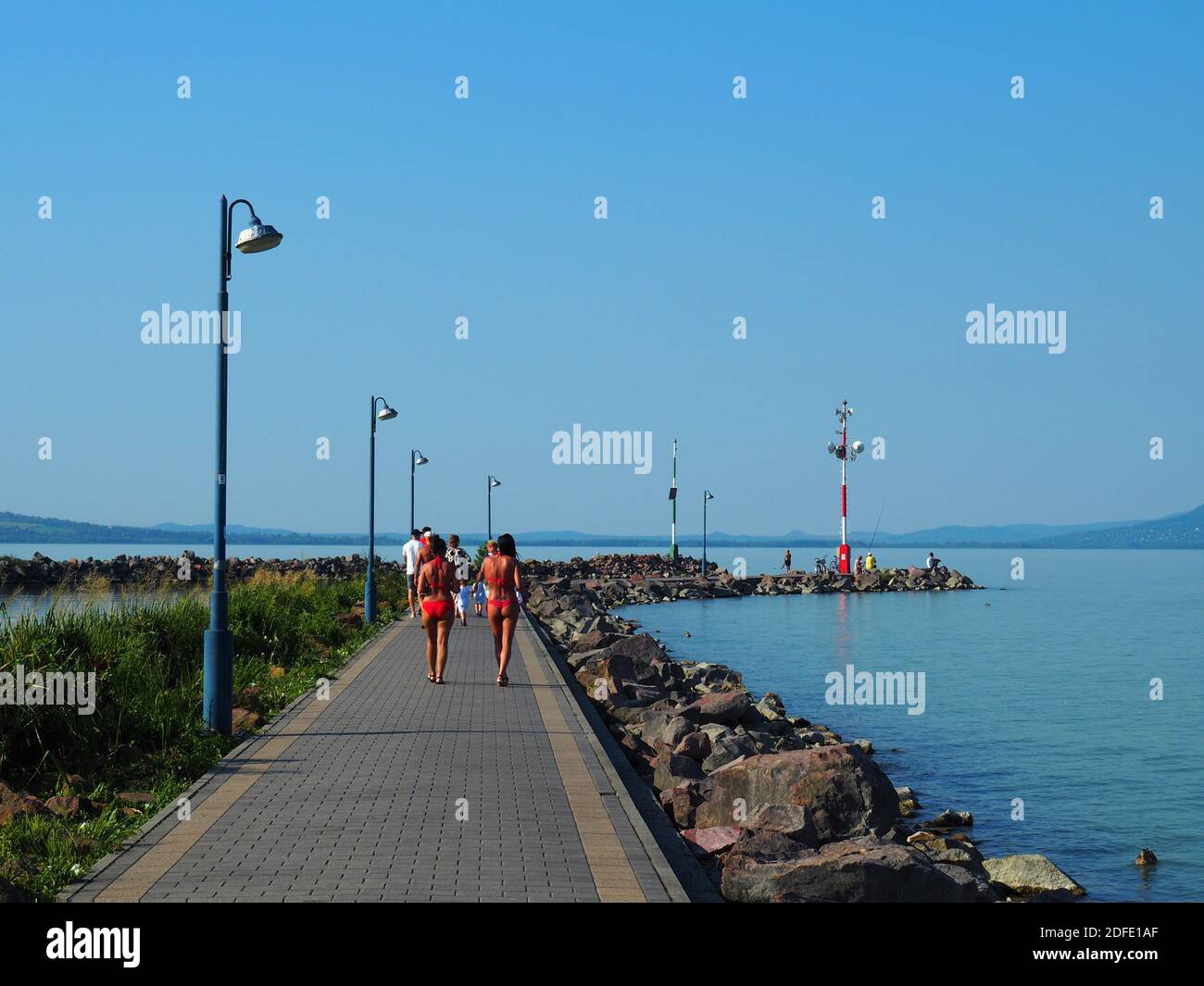 Balatonmáriafürdő, Hungary - July 30, 2020: Women in red bikini walking on the pier at a canal of the lake Balaton Stock Photo
