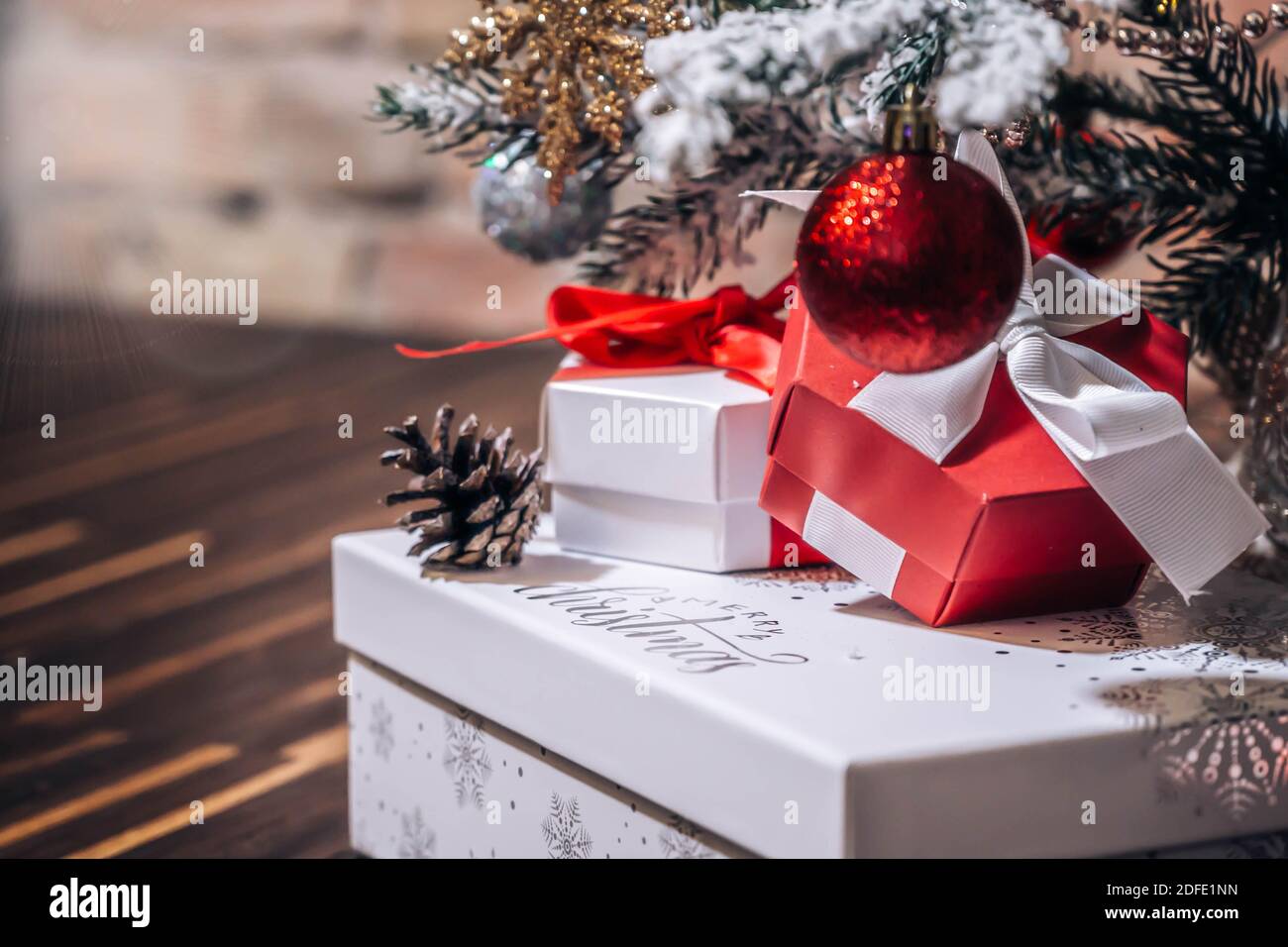Christmas presents under the tree. Christmas Gifts. Background with Christmas gifts under Christmas tree isolated on a wooden background. Copy space. Stock Photo