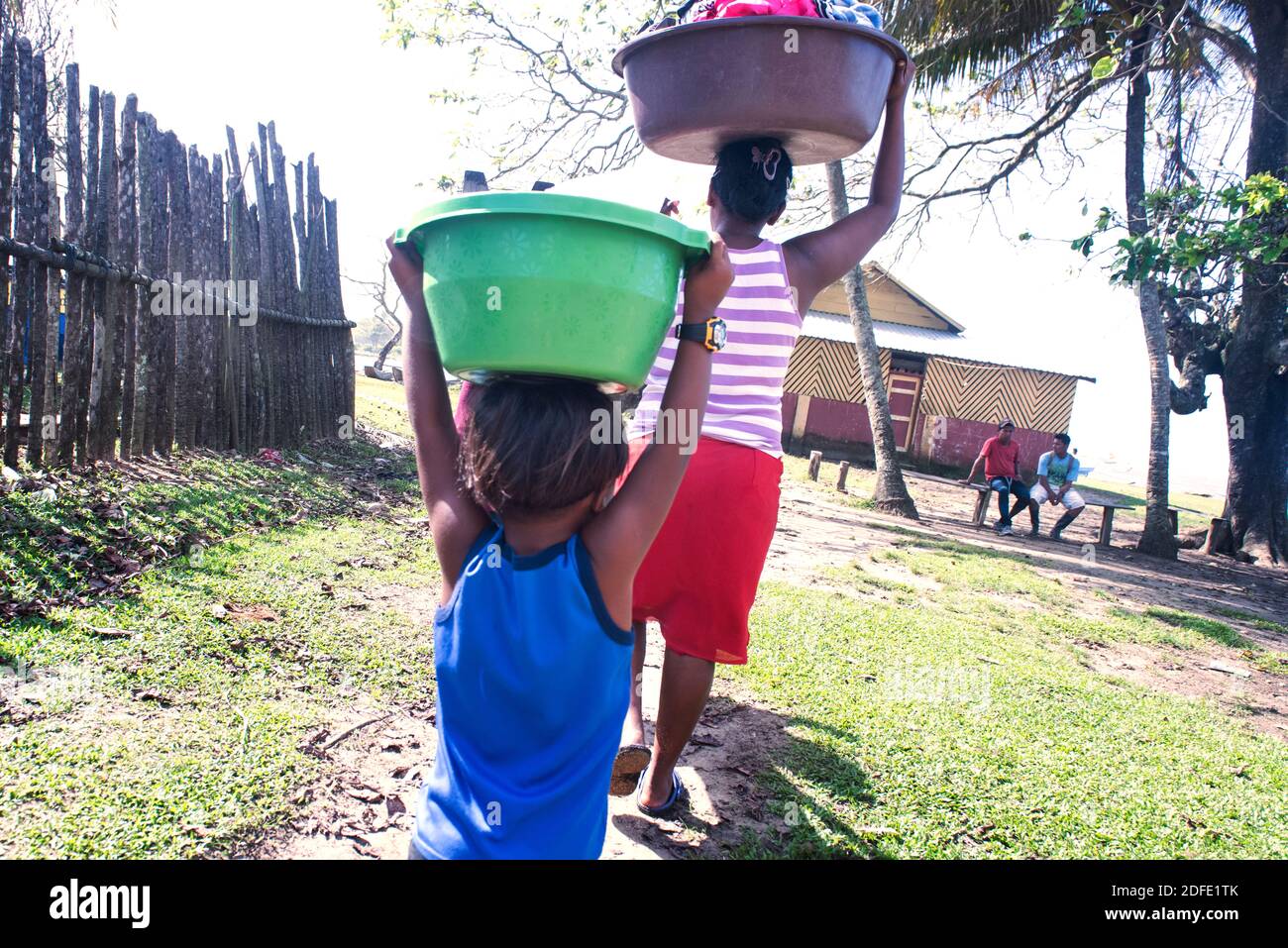 Young Boy helping his mother carrying a laundry basket on his head. Rio Platano, Mosquitia, Honduras Stock Photo