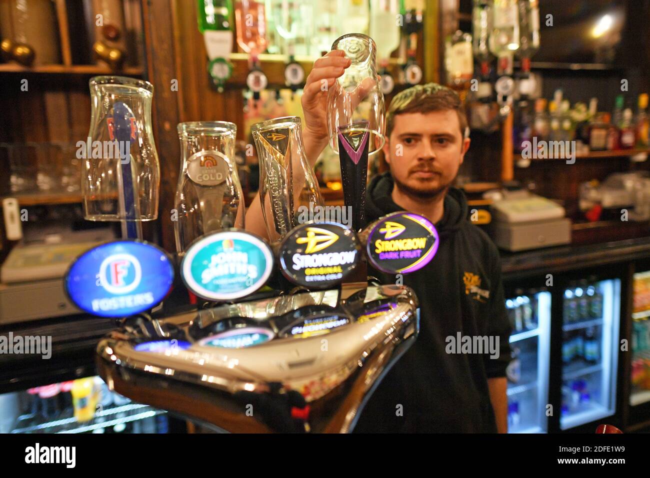 David Morgan, supervisor at The Borough pub in Cardiff, puts glasses on top of the beer taps ahead of closing for two weeks as pubs, bars, restaurants and cafes are forced to stop selling alcohol and shut by 6pm as part of a new round of coronavirus restrictions that come into force in Wales on Friday night. Stock Photo
