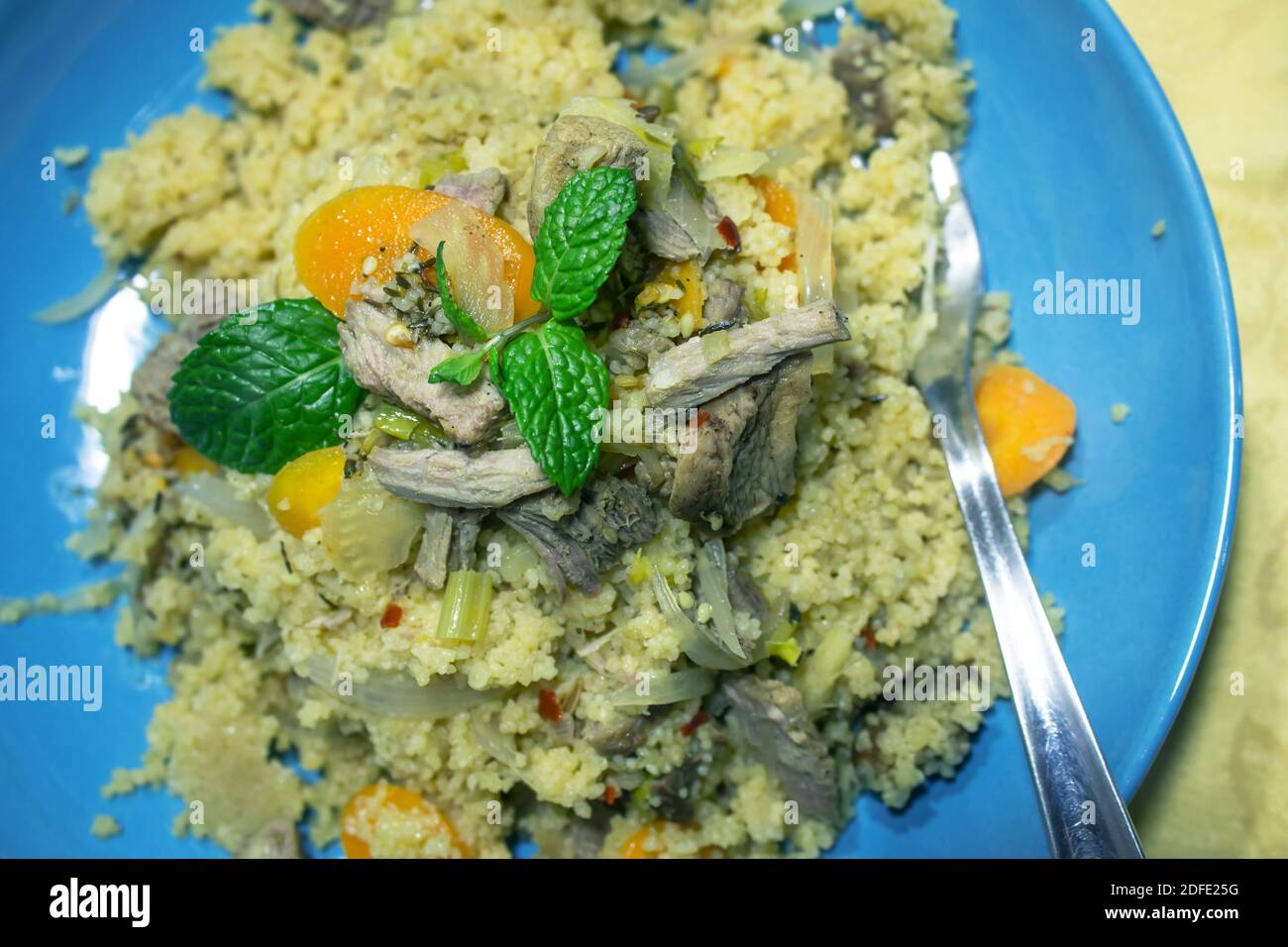 Couscous made from turkey meat and vegetables in a blue dish Stock