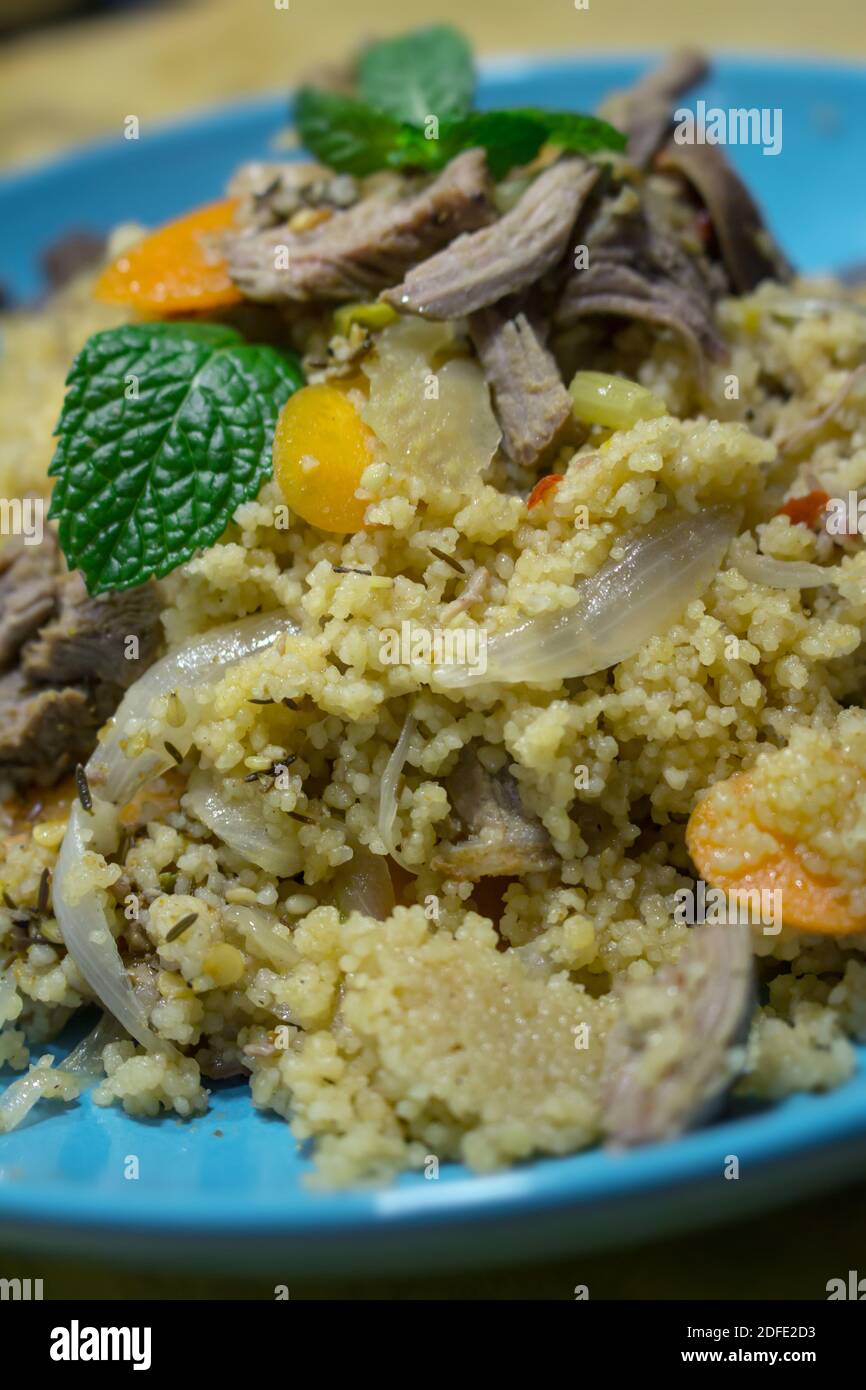 Couscous made from turkey meat and vegetables in a blue dish Stock