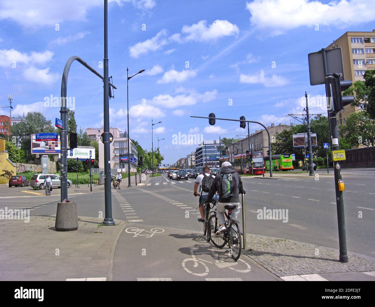 Cyclists at crossroads of big street waiting for green traffic light. Sports family moving around city on bicycle. Couple riding bicycles along city s Stock Photo