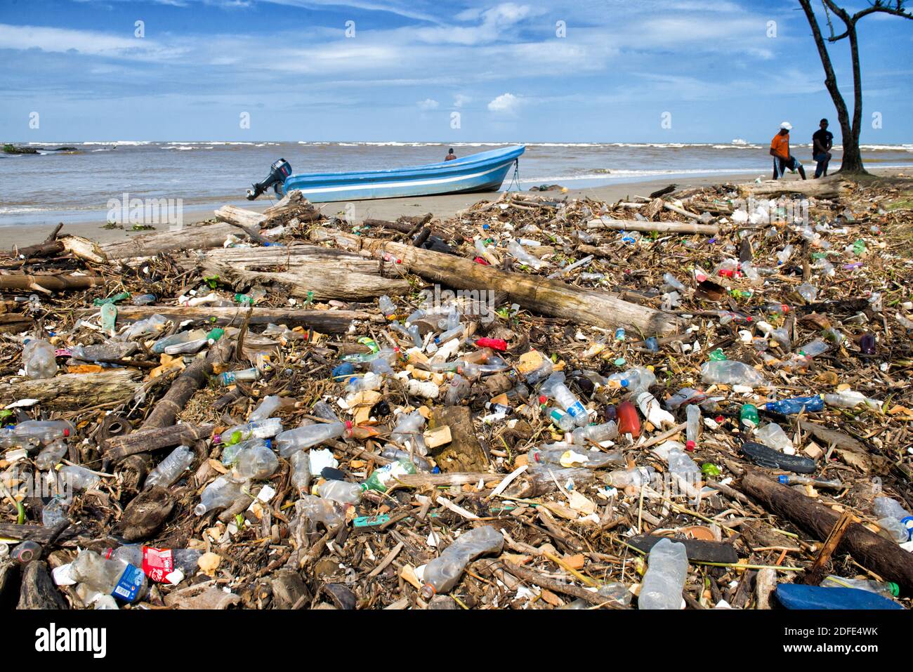 Caribbean beach full of plastic trash with fishing boat behind. Barra Platano, Mosquitia, Honduras Stock Photo