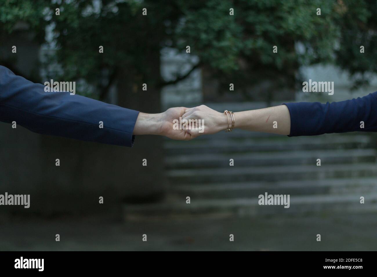 A closeup shot of a stylish couple reaching out and holding hands Stock Photo