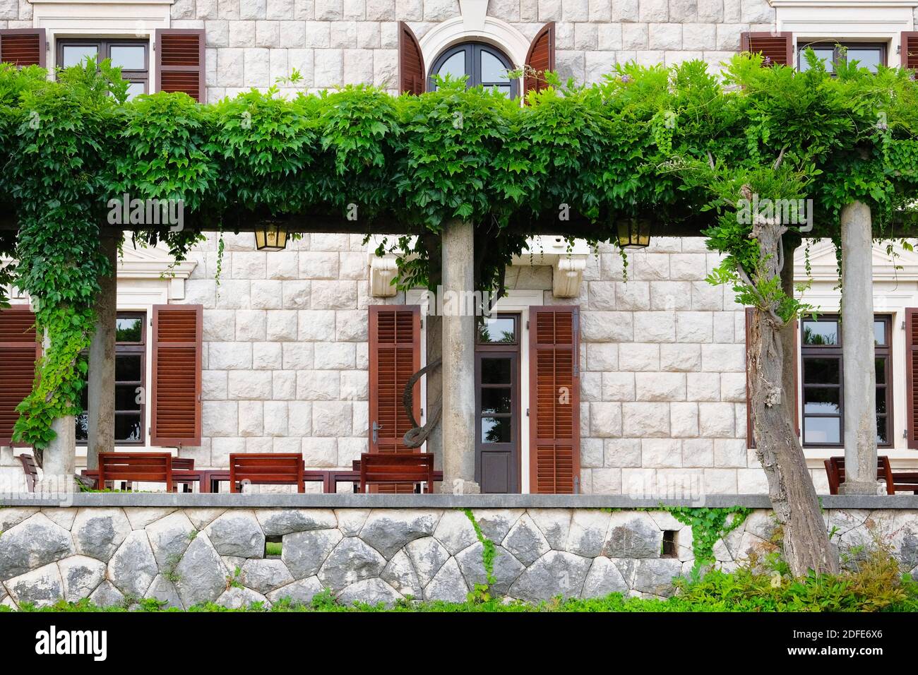 Pergola with green plants in front of hotel on Mediterranean coast. Landscaping and decoration of hotel exterior. Stock Photo