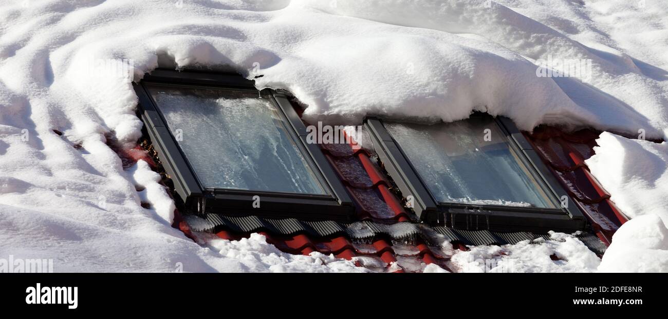 Tiled roof with glass attic windows covered with snow after snowfall ...