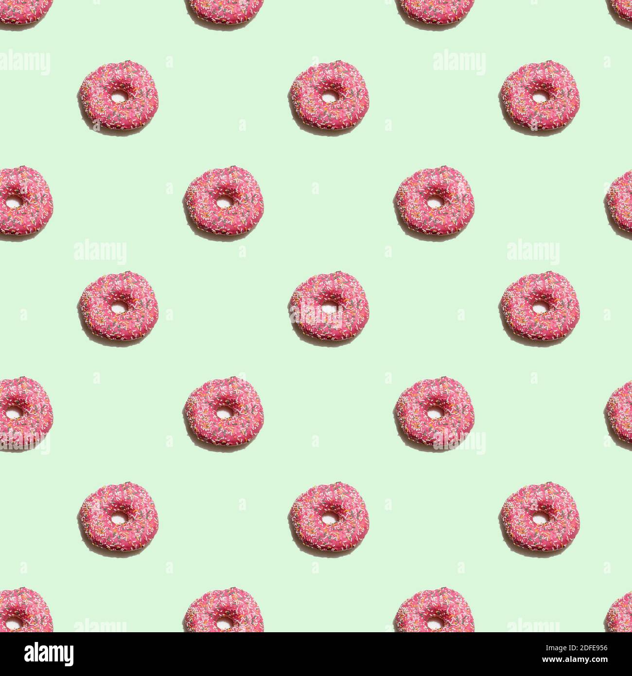Seamless pattern with pink glazed donuts on the pastel green background ...