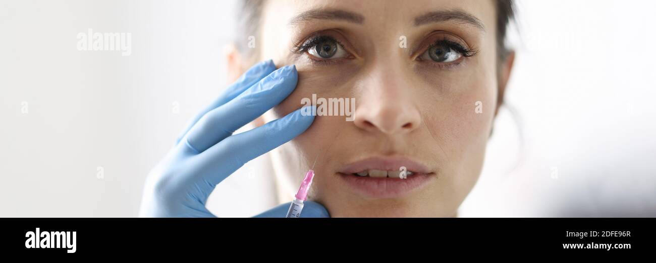 Doctor gives woman an injection into nasolabial fold. Stock Photo