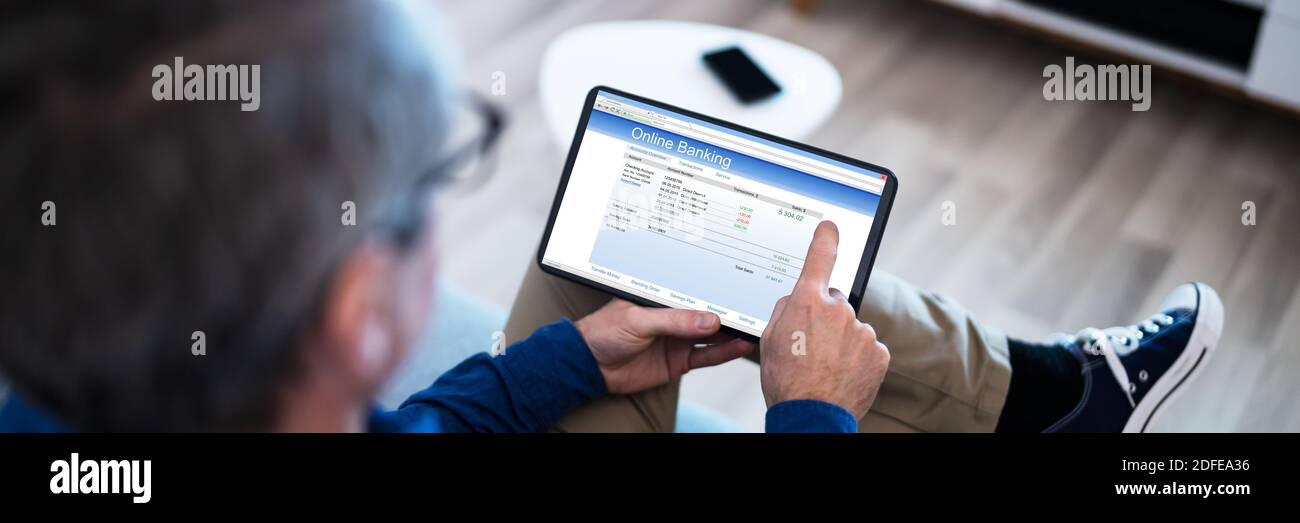 Man Using Tablet Computer Checking Bank Statement Online Stock Photo