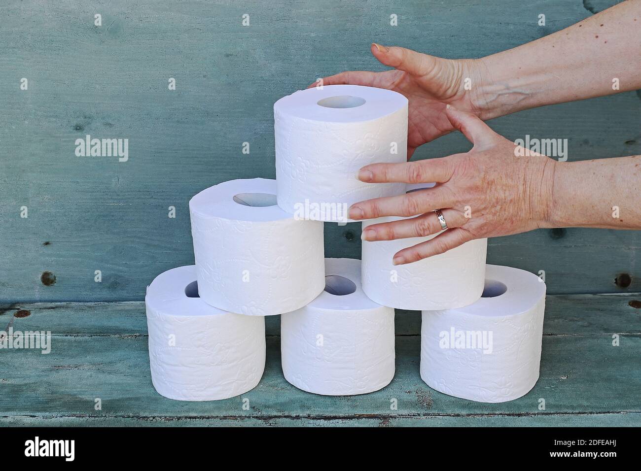 A woman takes a roll of toilet paper from a stack. Mass purchase of toilet paper Stock Photo Alamy