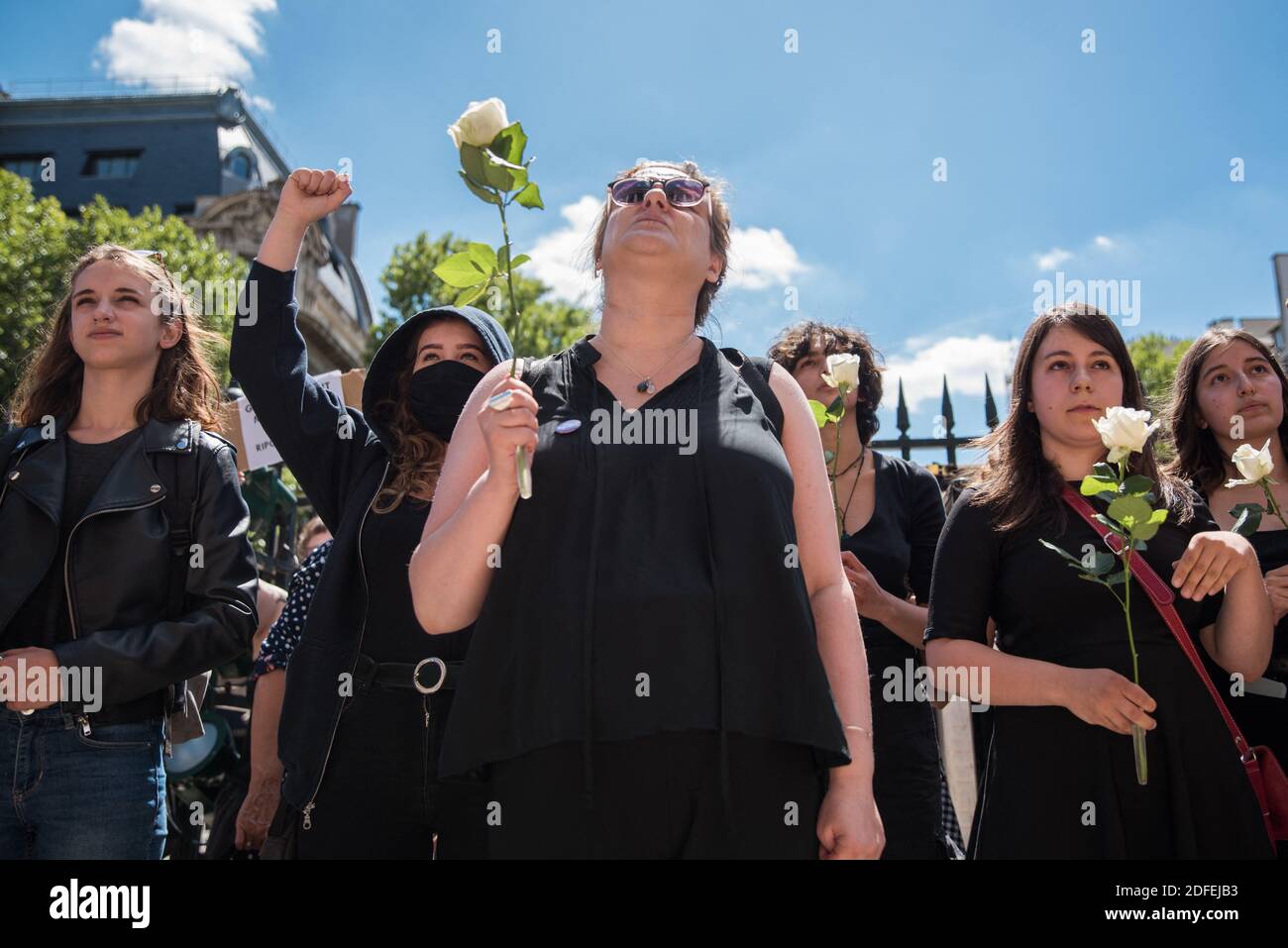 Women dressed in black, sing and hold signs and white roses during a fake  funeral organised by "Nous toutes" as part of a happening against the  nomination of Darmanin and Dupond Moretti