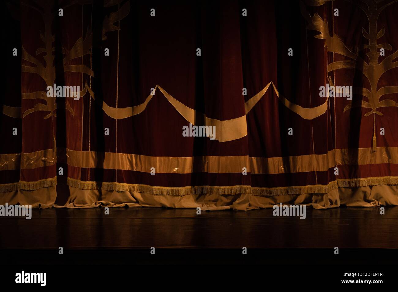 Theatrical dark red velvet curtain with golden fringe. Texture ...