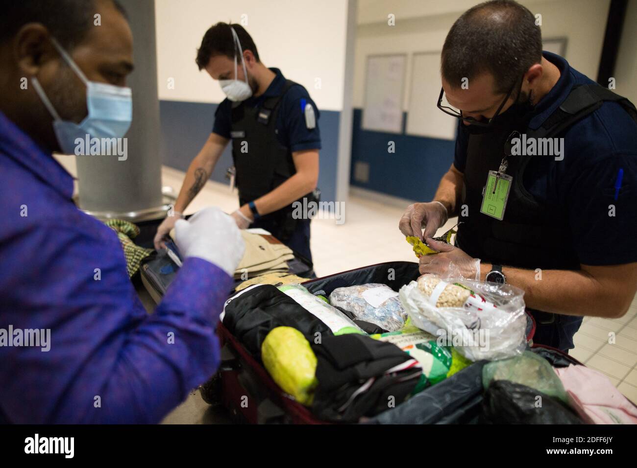 Customs officer wearing face mask during a search of the luggage of a