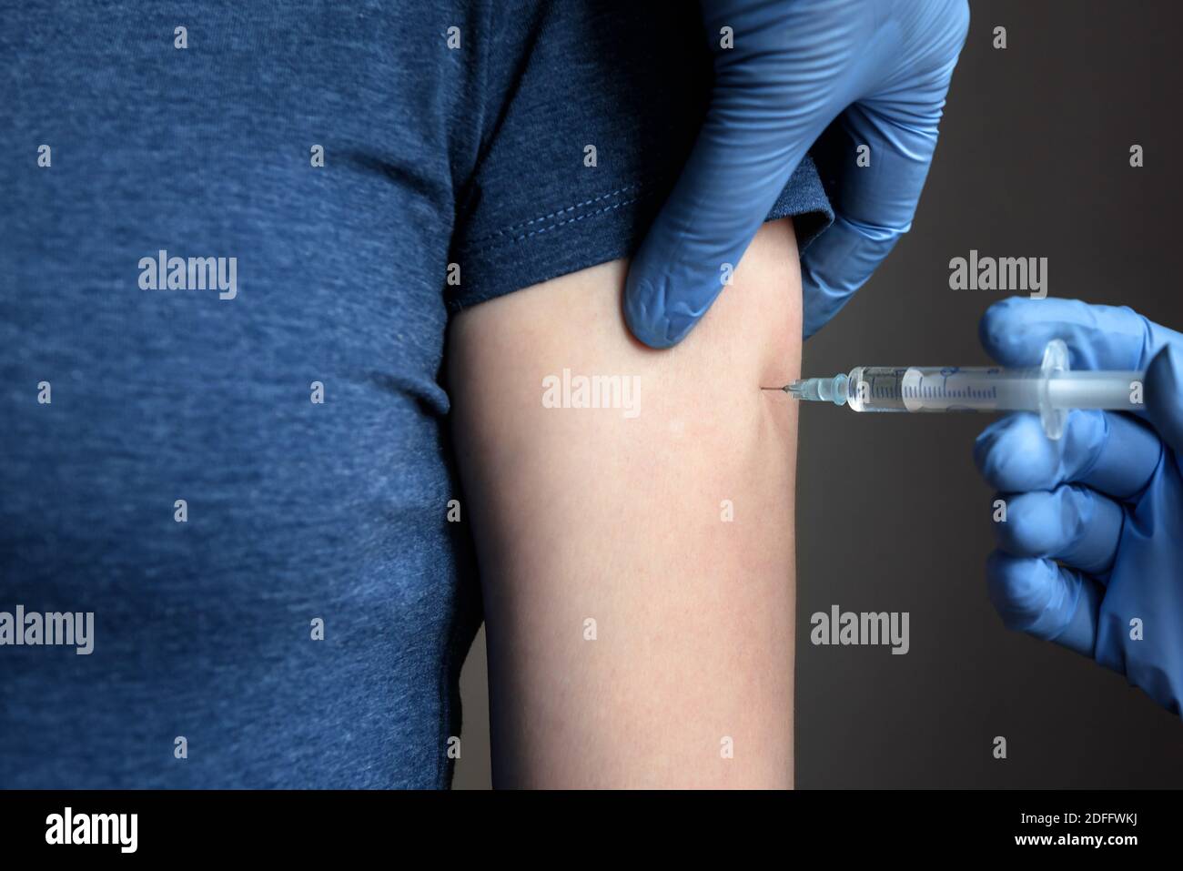 COVID-19 vaccine injection, doctor in gloves holds syringe and makes jab to woman patient in clinic. Prevention of coronavirus or influenza. Concept o Stock Photo