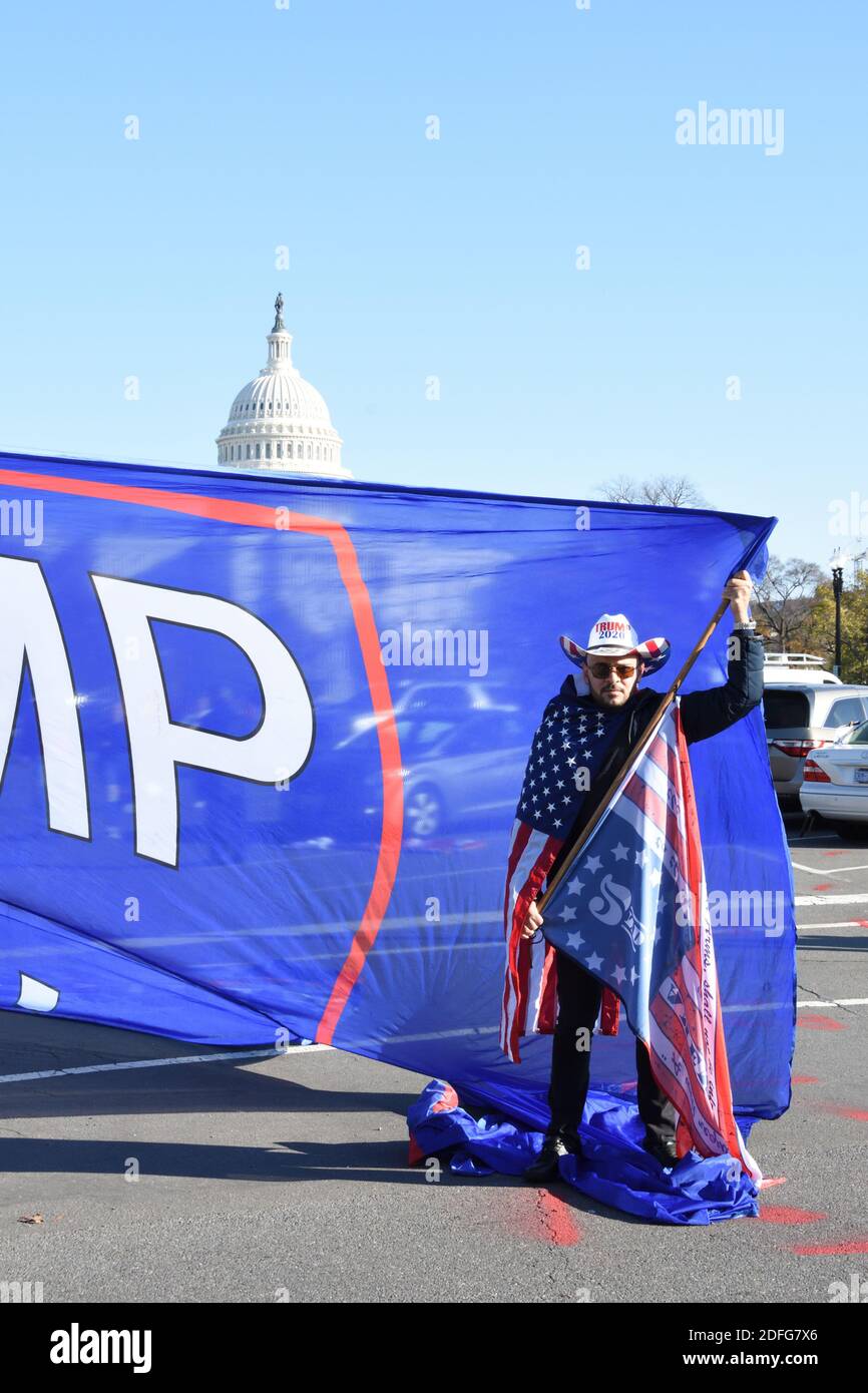 Washington DC. Nov 14, 2020. Million Maga March. A man with Trump cowboy hat, wrapped in American flag, holding Trump banner at US Capitol building. Stock Photo