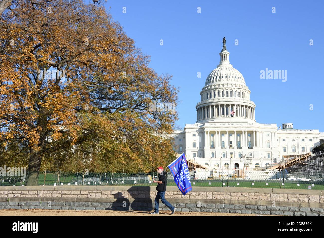 Washington DC. November 14, 2020. Million Maga March. A man with red cap walking with Trump 2020 flag in front of the US Capitol building. Stock Photo