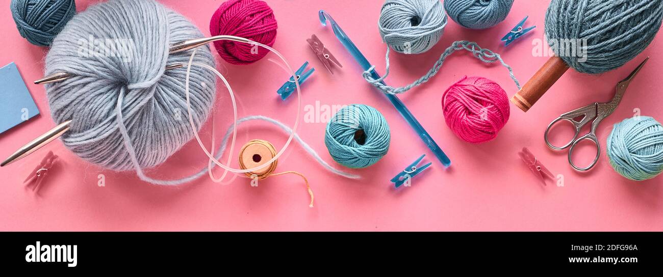 Various wool yarn and knitting needles, creative knitting hobby. Panoramic background on pink. Stock Photo