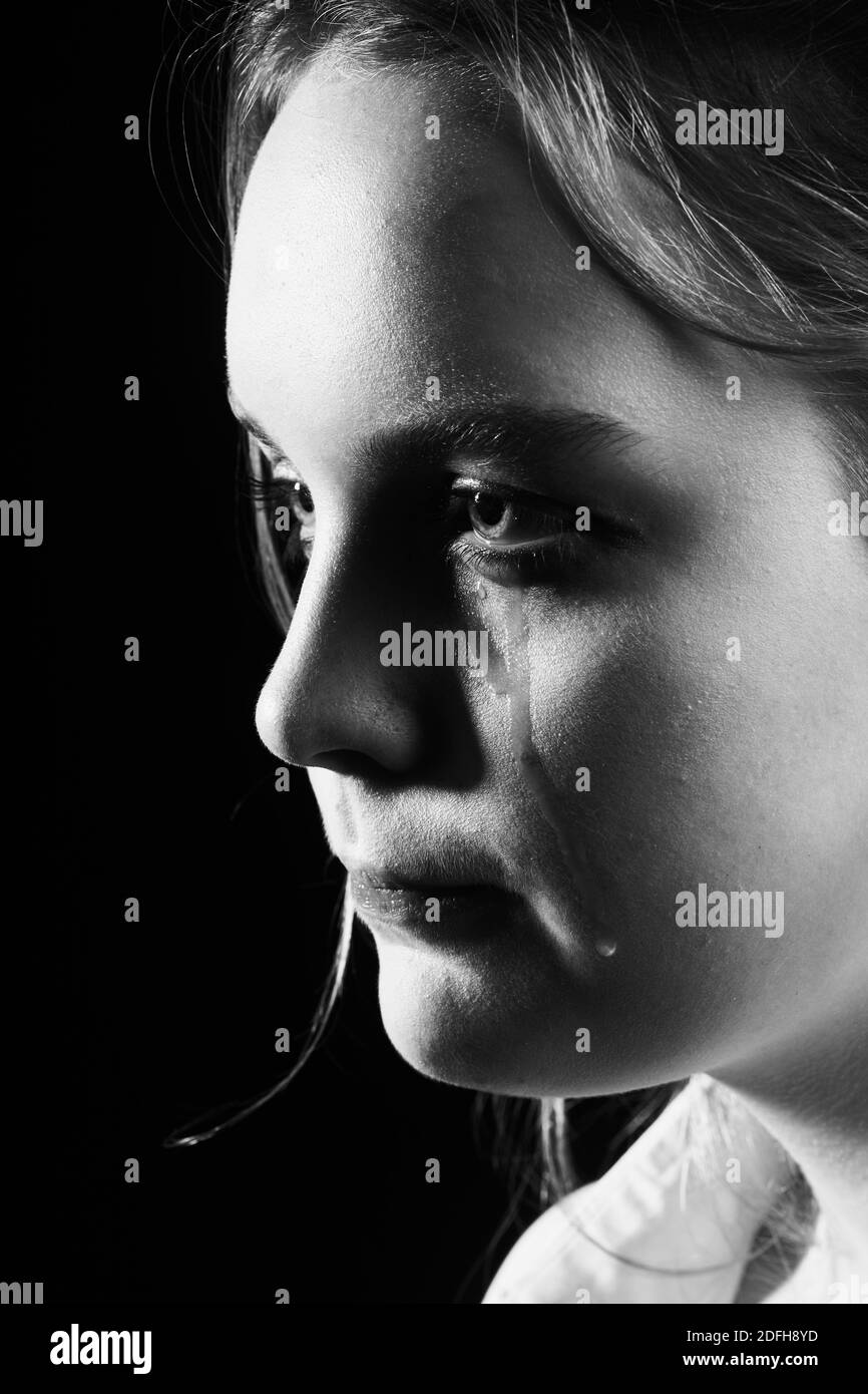 sad woman crying, looking aside on black background, closeup portrait, profile view, monochrome Stock Photo