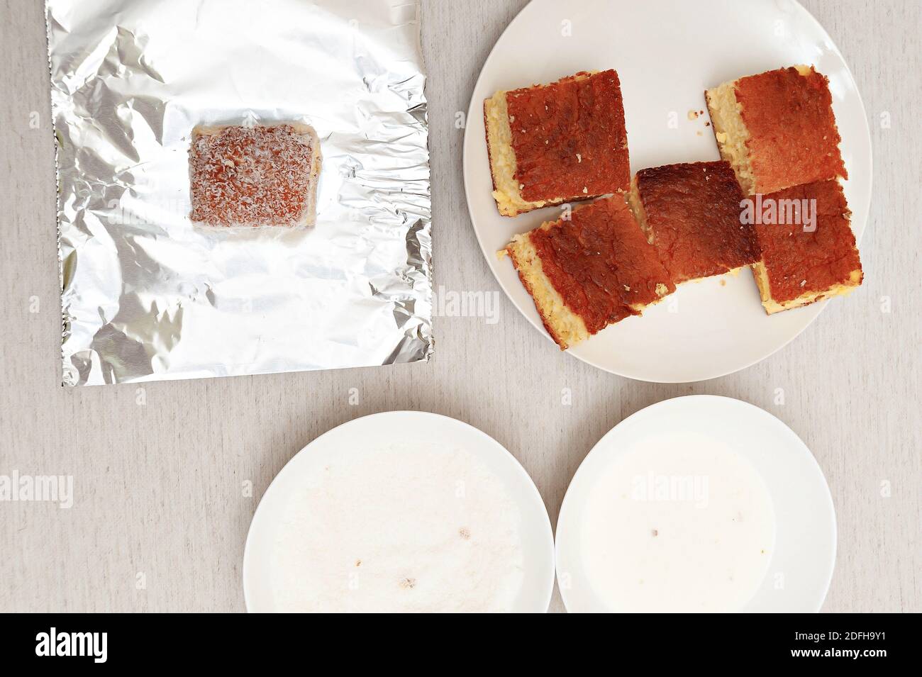 Pieces of cake, aluminum foil, plates with milk and grated coconut. Top  view Stock Photo - Alamy