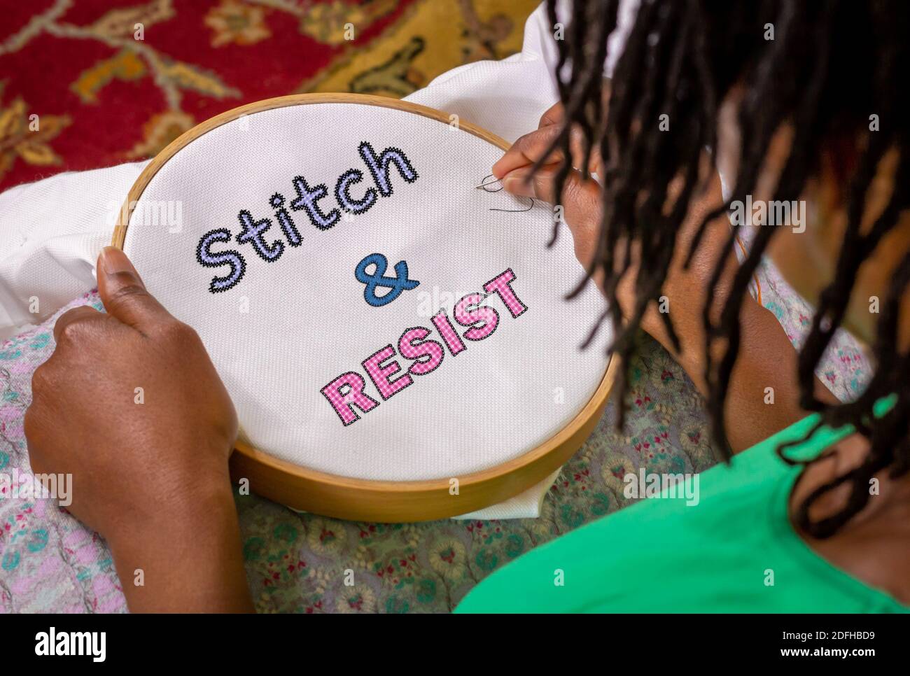 craft activism, woman sewing Stitch and Resist embroidery on hoop, craftivism ethnic feminist activism. Stock Photo