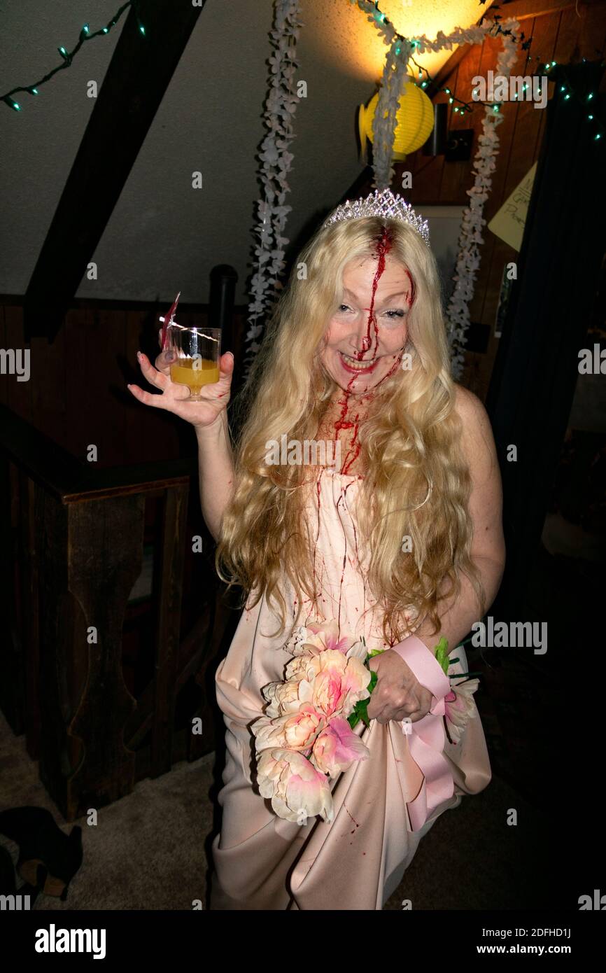 Beautiful woman with drink, blood on her face, crown and costume on a ski trip costume party. Ironwood Michigan MI USA Stock Photo