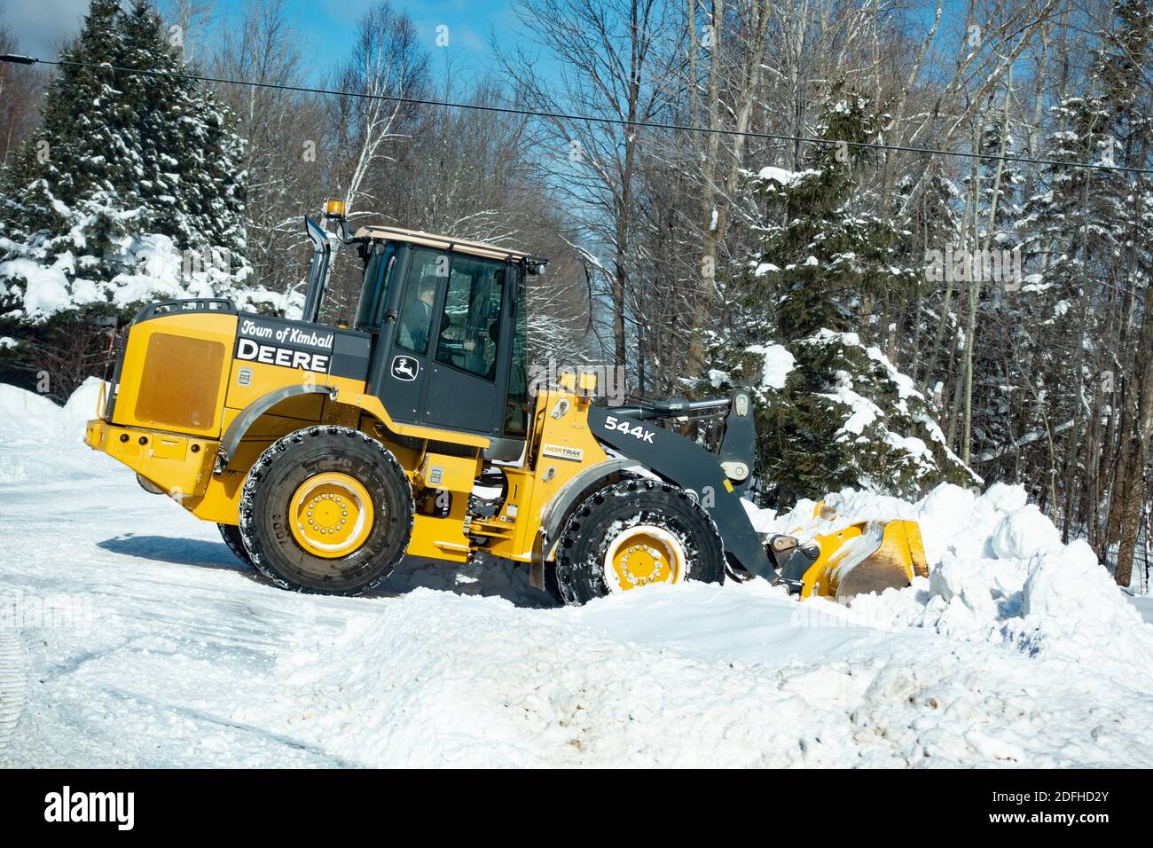 Deere front end loader plowing clearing the snow on side of the road