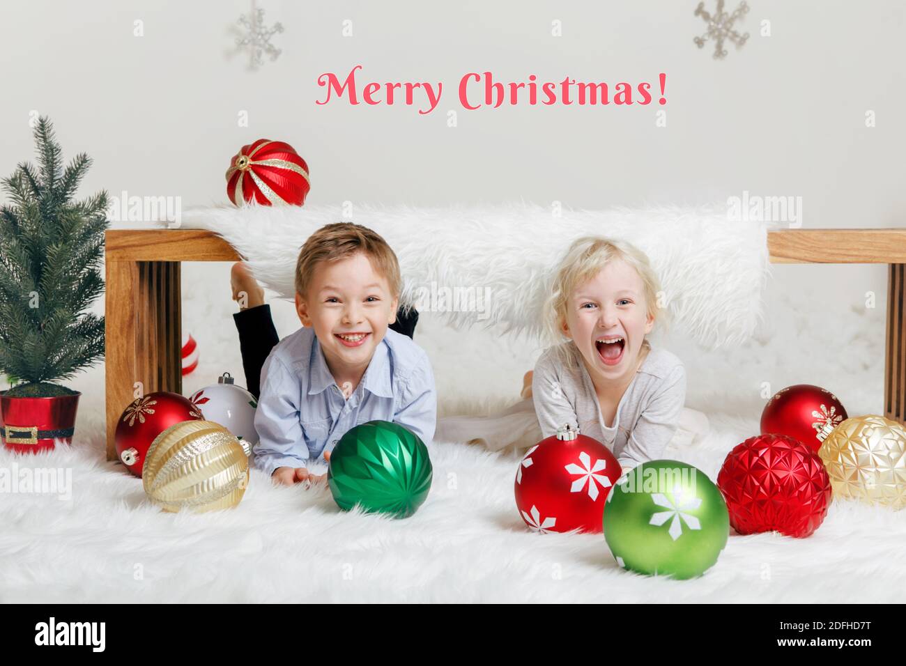 Merry Christmas text card. Happy smiling Caucasian children friends in festive holiday decoration. Kids celebrating Christmas or New Year. Little cute Stock Photo