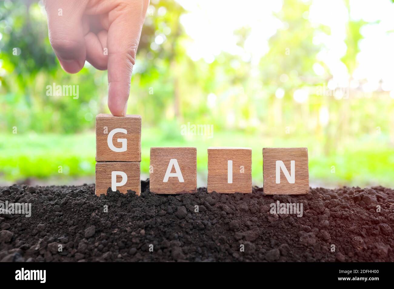 No pain no gain concept. Hand changing pain word to gain in wooden blocks on natural background. Stock Photo