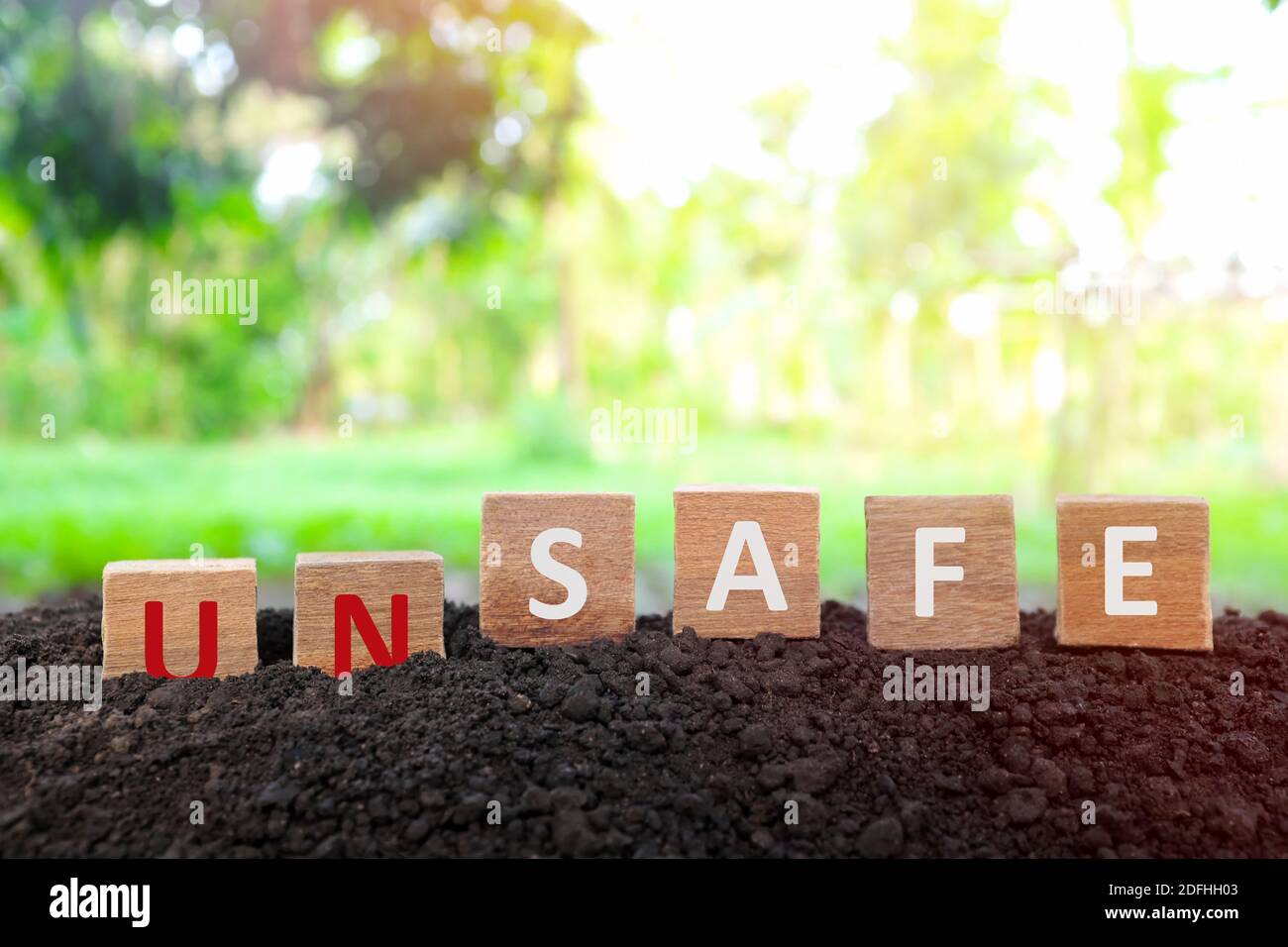 Hand changing word unsafe to safe in wooden blocks on natural background. Safety on workplace and precautionary safe acts to prevent accident concept Stock Photo