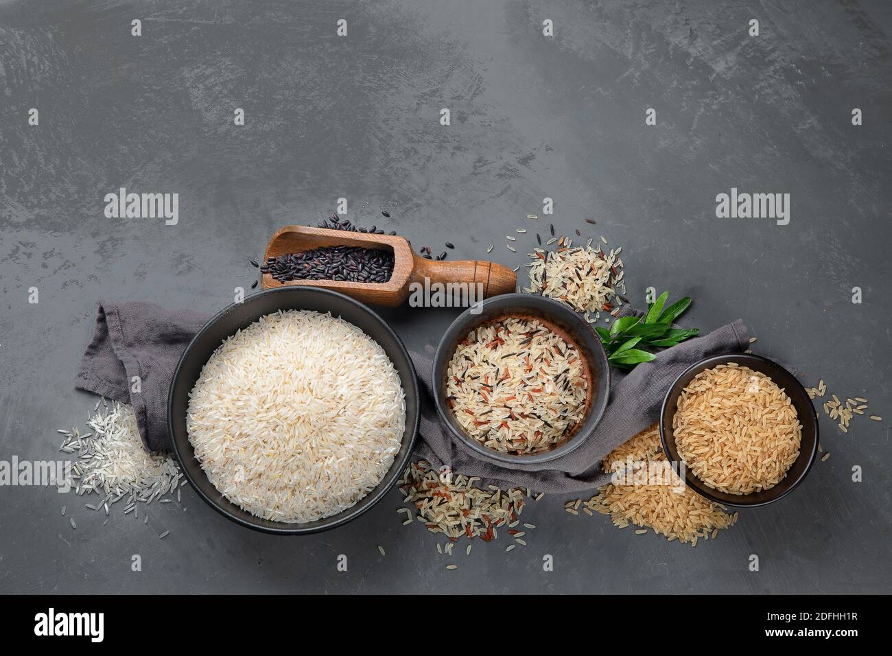 Set with different types of rice on grey background, top view with copy ...