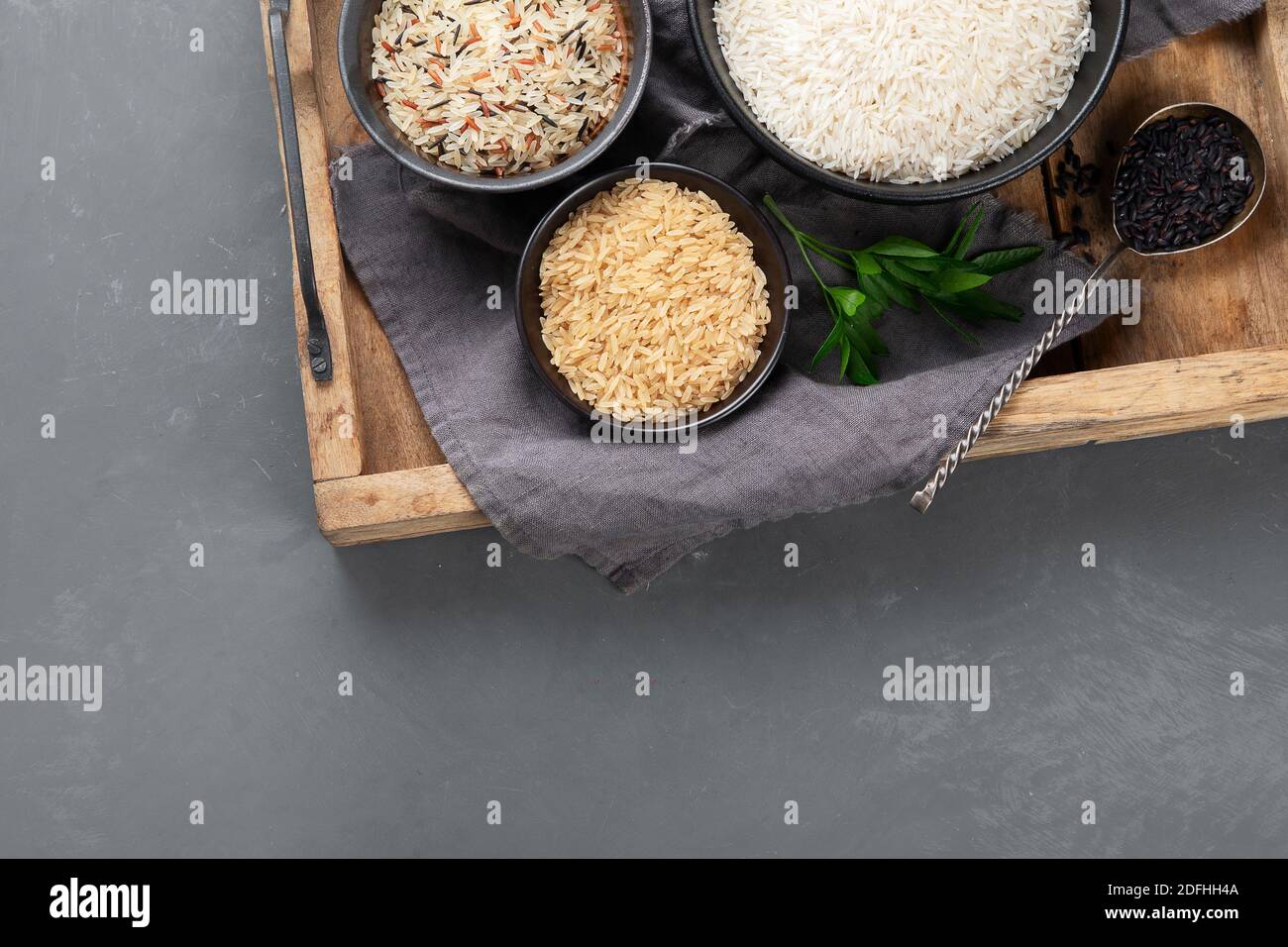 Set with different types of rice on grey background, top view with copy ...