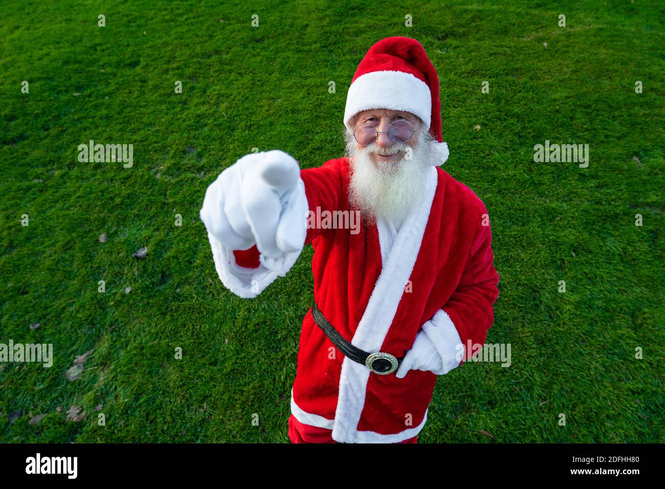 Christmas. Smiling Santa Claus in white gloves points his finger to the camera. against the background of the street. Stock Photo