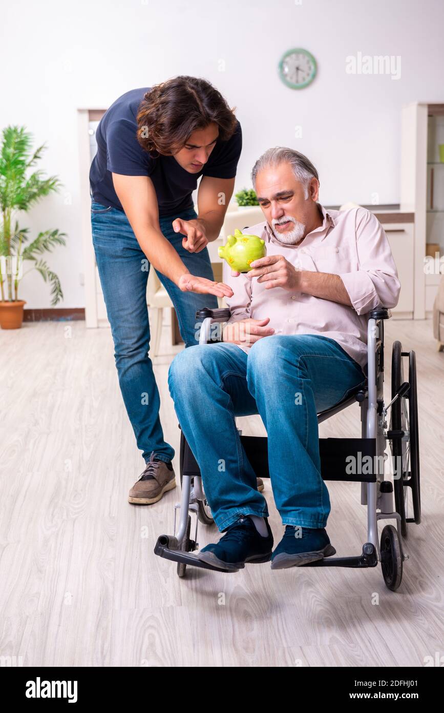 Old man in wheel-chair and bad caregiver indoors Stock Photo