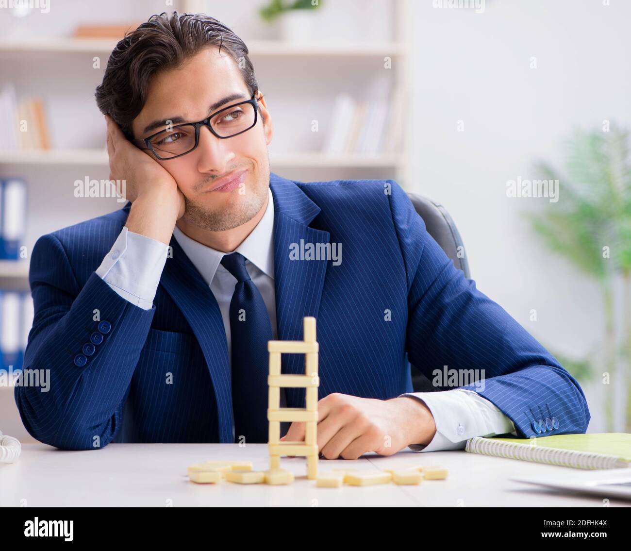 The young businessman building domino tower in office Stock Photo - Alamy