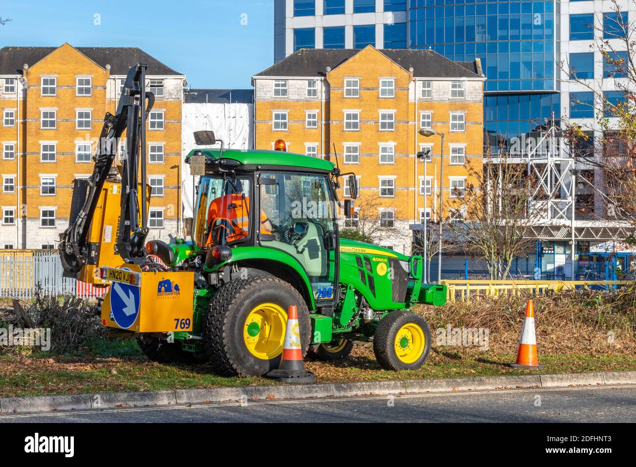 a tractor with a hedge cutting attachment working at the roadside cutting back vegetation and carrying out highway maintenance. Stock Photo