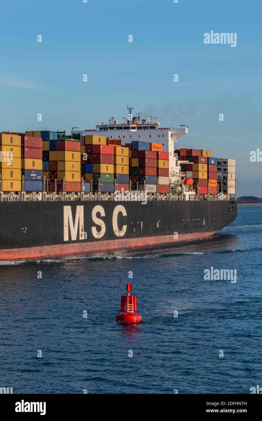 large container ship entering southampton docks passing a red coloured buoy in the main channel