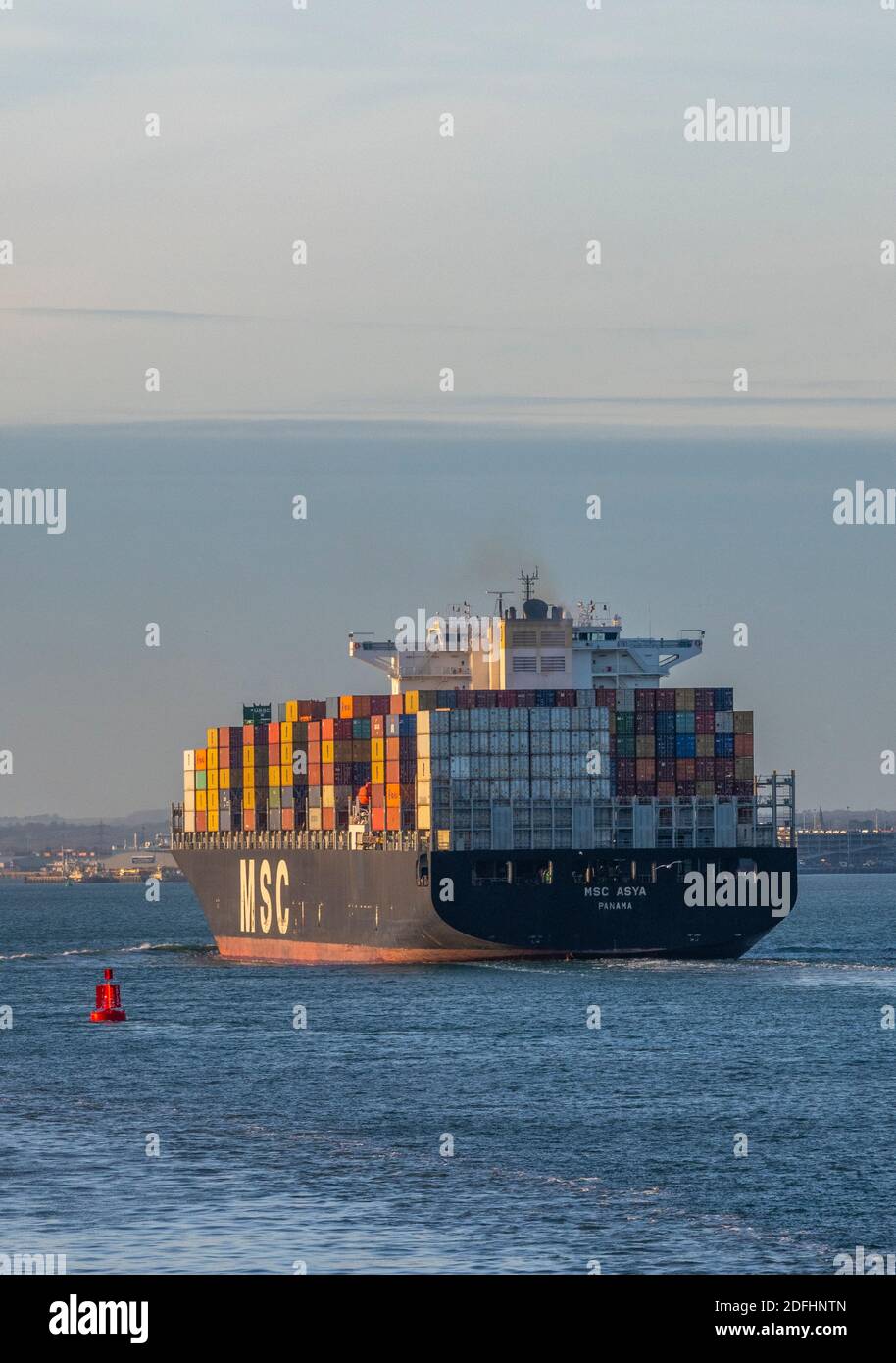 a large container ship MSC asya entering the port of southampton docks with a full cargo or load of colourful containers on board. Stock Photo
