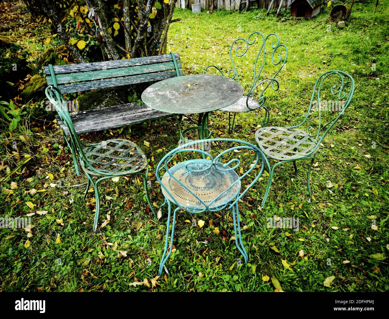 An old vintage metal garden furniture on a fresh grass lawn with fallen  autumn leaves Stock Photo - Alamy
