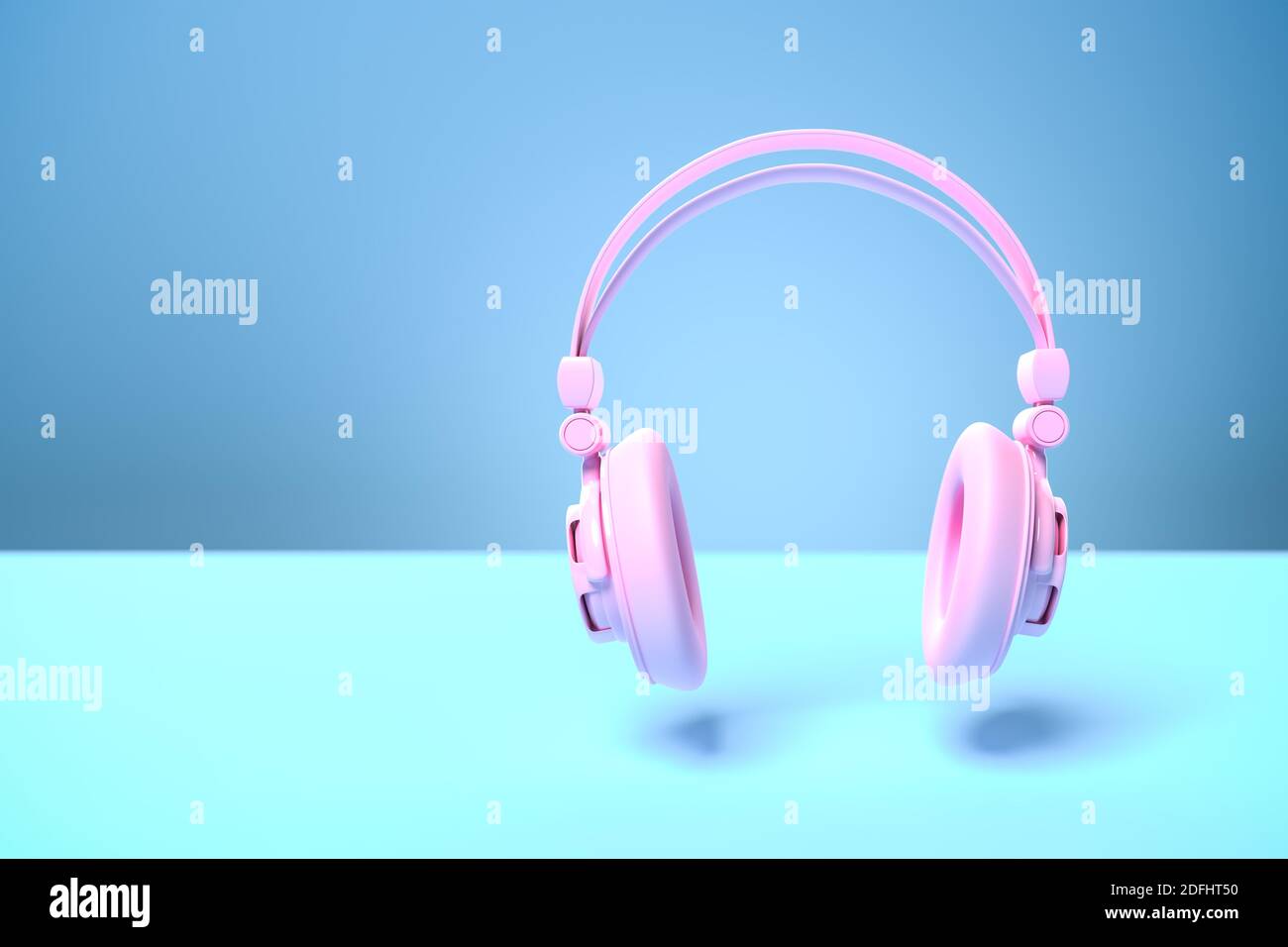 Music concept: A pink headphone against a blue background with shadow. Copy space - selective focus on foreground Stock Photo