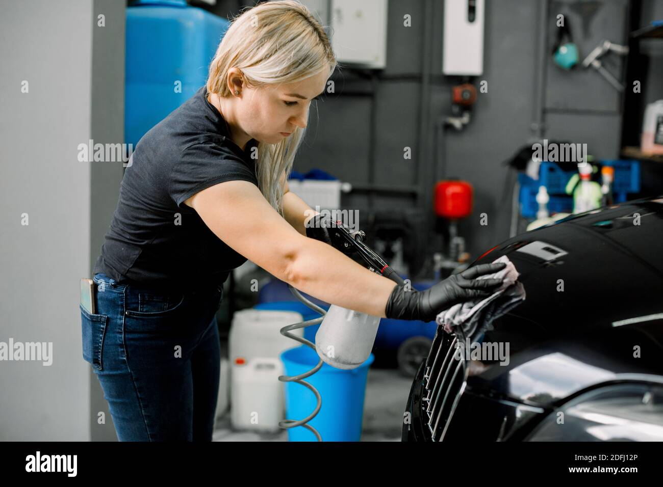 Pretty young female worker of car wash and detailing service