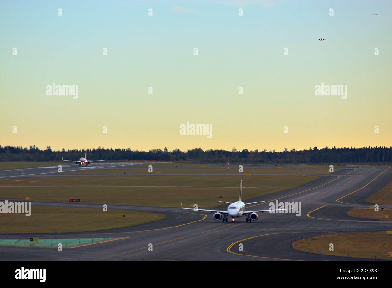 Taxiing and landing airplanes and two airplanes in the air in queue to land Stock Photo