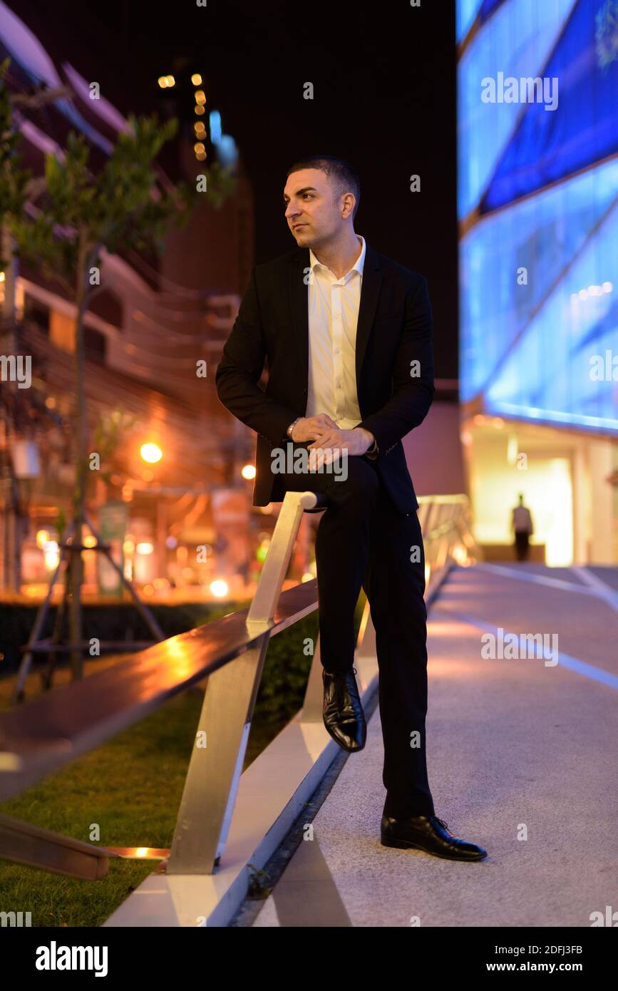 Portrait of businessman wearing suit and thinking outdoors at night in ...