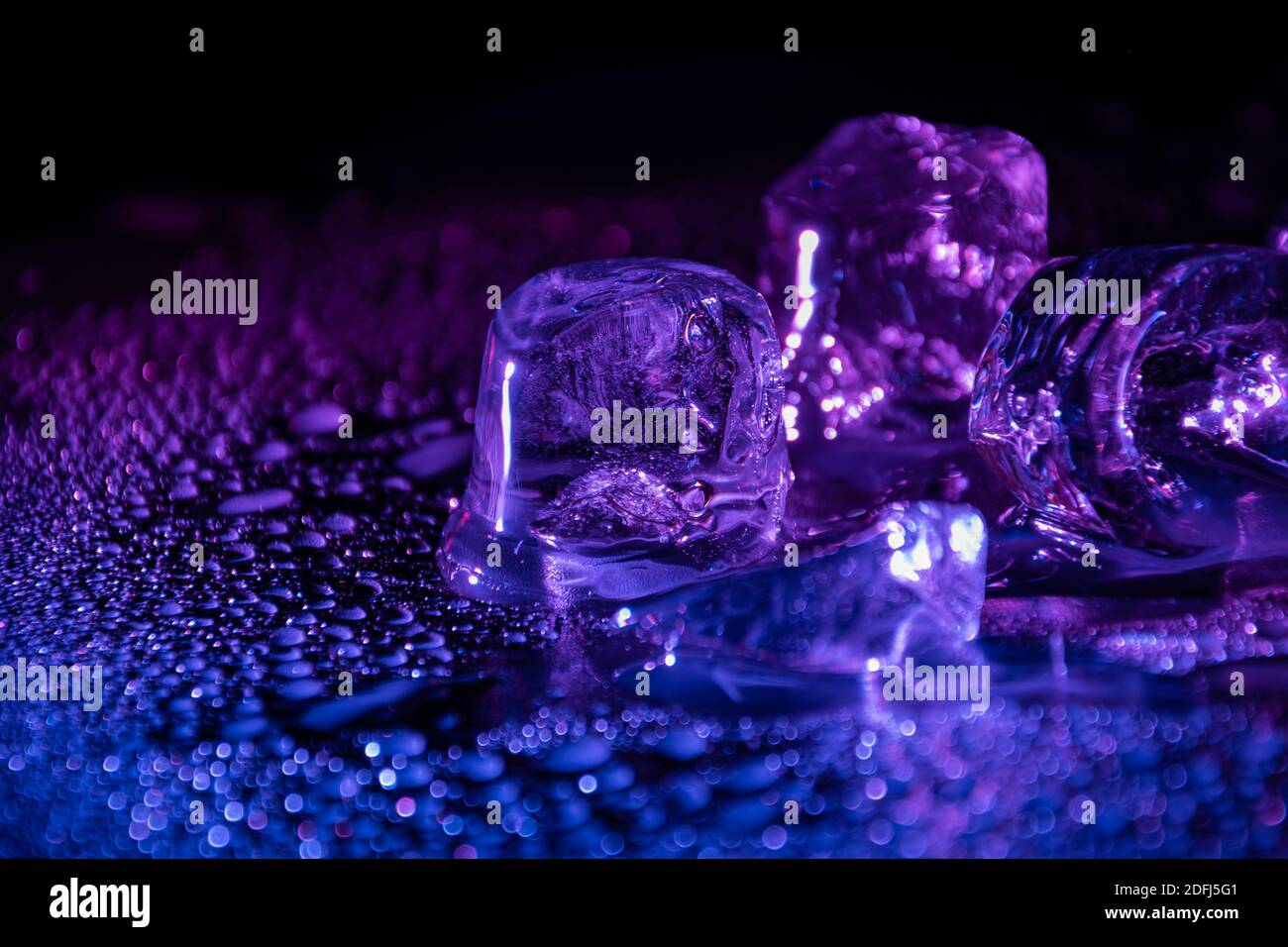 Melting frozen ice cubes illuminated with blue coloured LED light in the  dark Stock Photo - Alamy