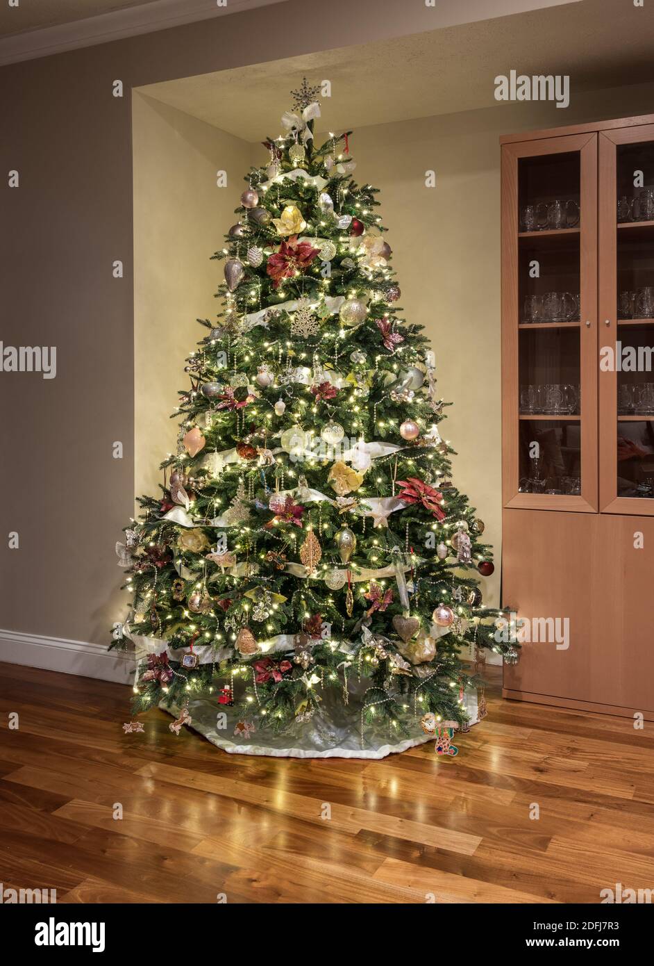 Carefully and beautifully decorated xmas tree in the corner of a modern home with wooden floors Stock Photo