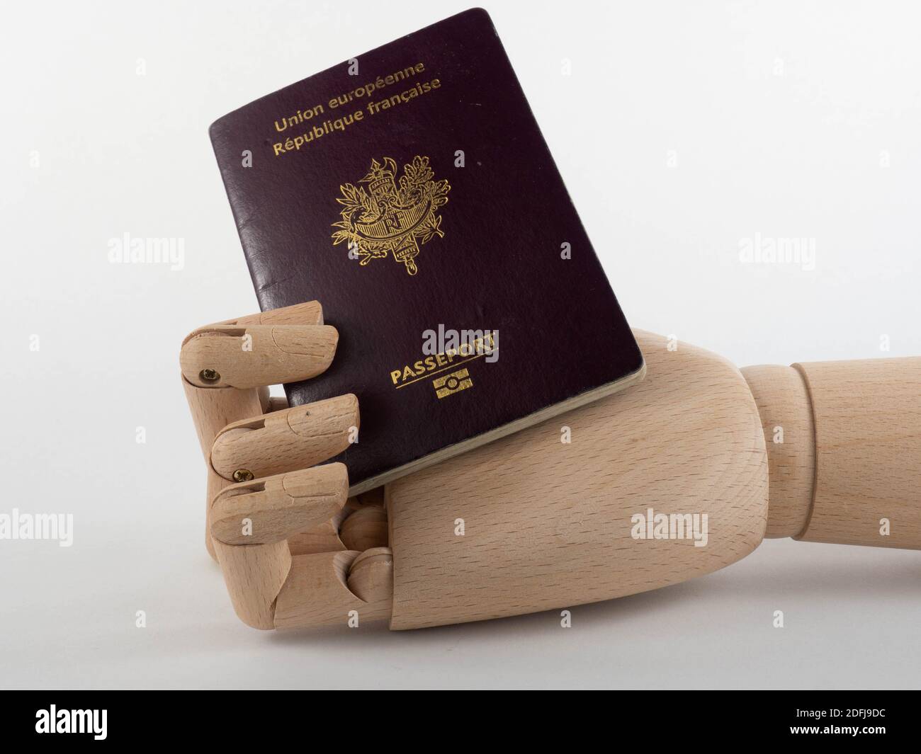 A wooden hand holding a French passport. Concept on travel and immigration. Stock Photo