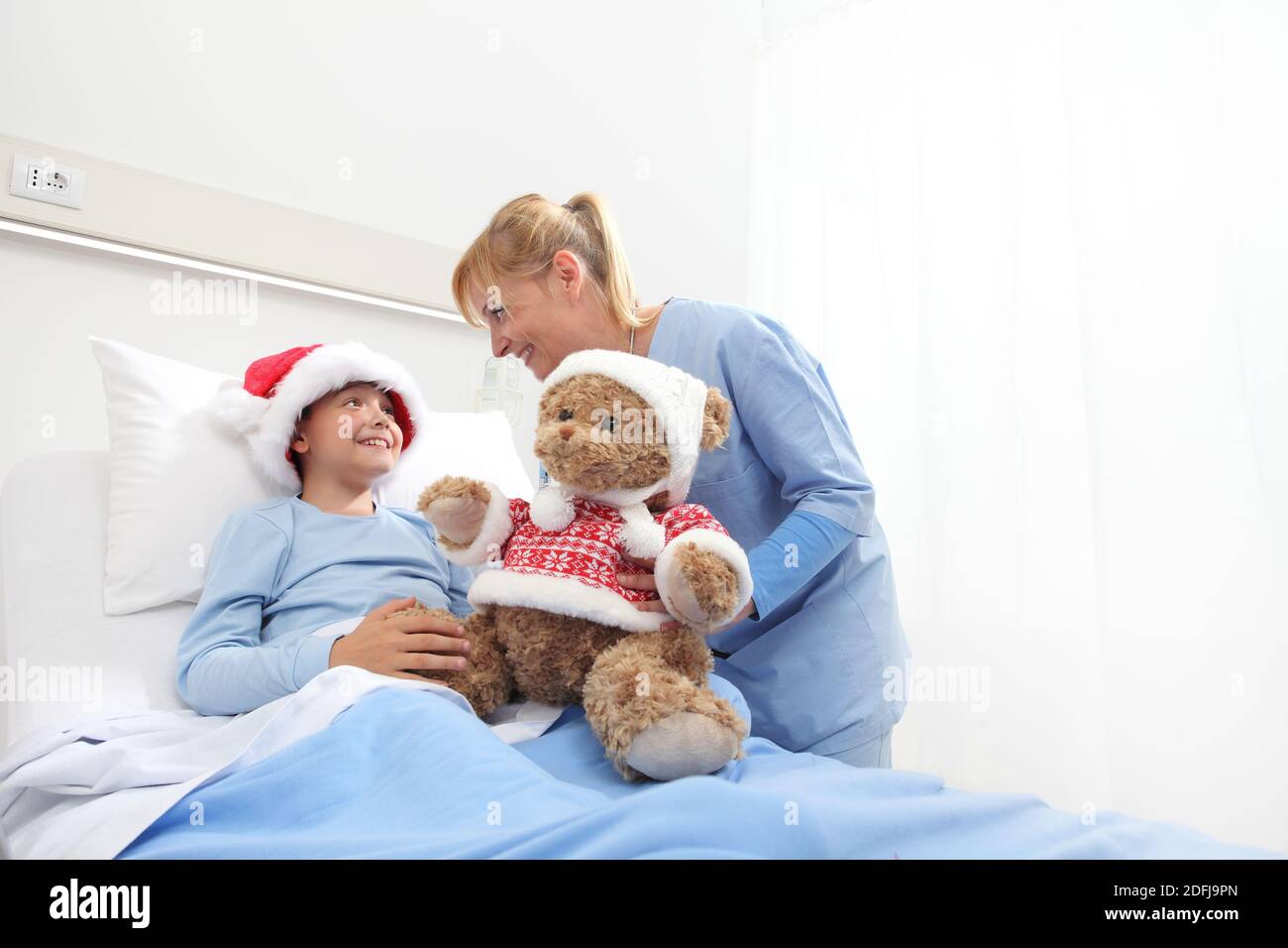 Christmas holiday in hospital happy child lying in bed with Santa Claus ...