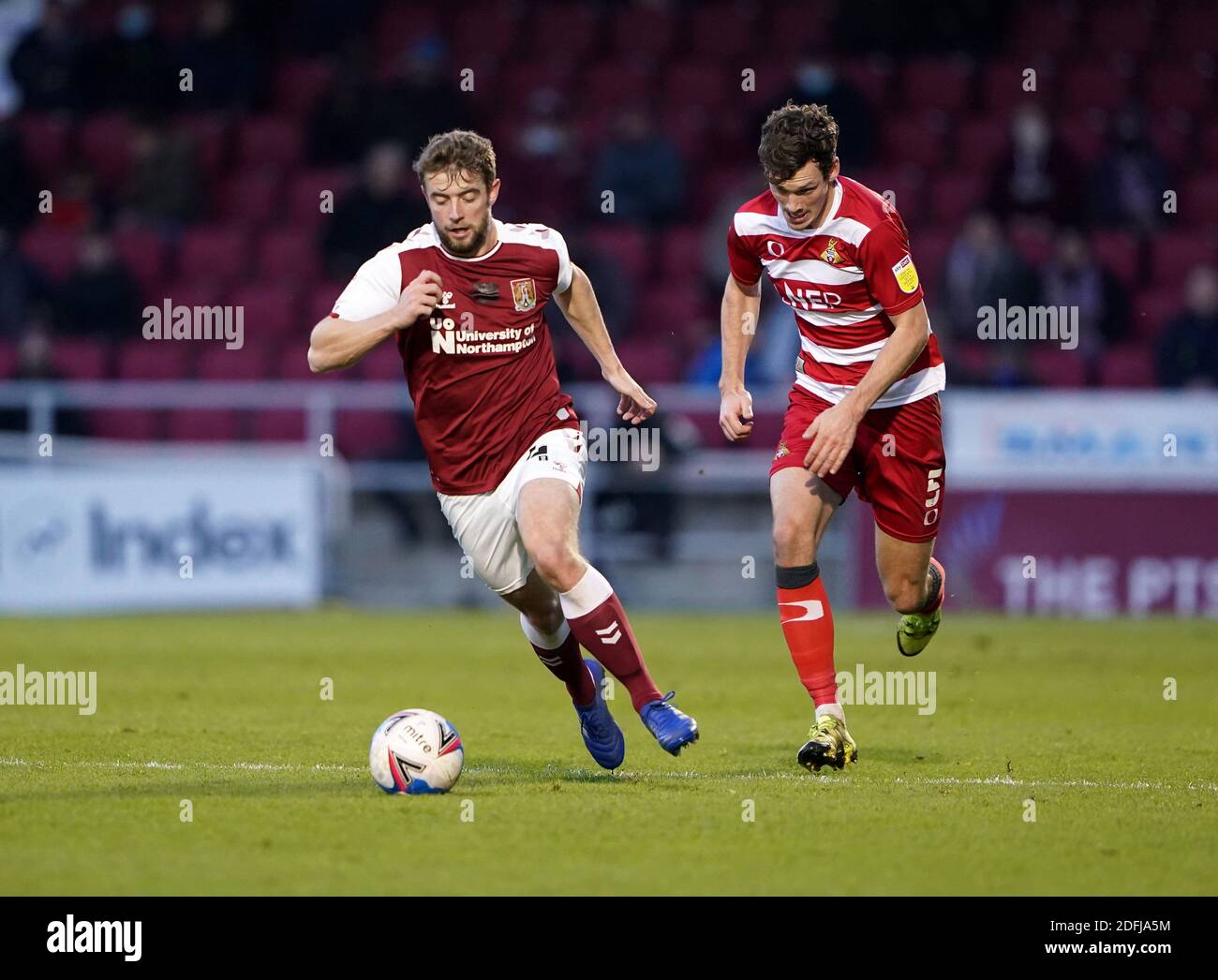 Northampton Town's Jack Sowerby (left) and Doncaster Rovers' Joe Wright battle for the ball during the Sky Bet League One match at PTS Academy Stadium, Northampton. Stock Photo