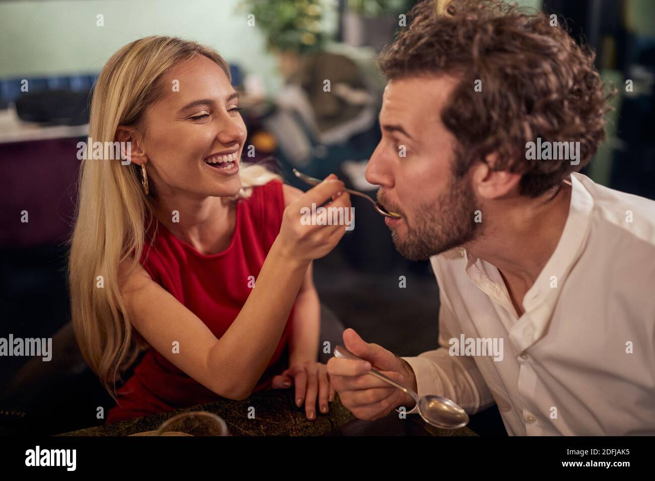 A young girl feeding his boyfriend at Valentine's day celebration at a restaurant in a relaxed atmosphere. Together, Valentine's day, celebration Stock Photo
