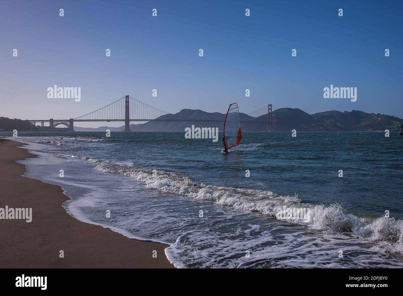 Windsurfer closing in on the beach in front of Golden Gate Bridge, a Kite-surfer in the distance, San Francisco, California, United States of America Stock Photo